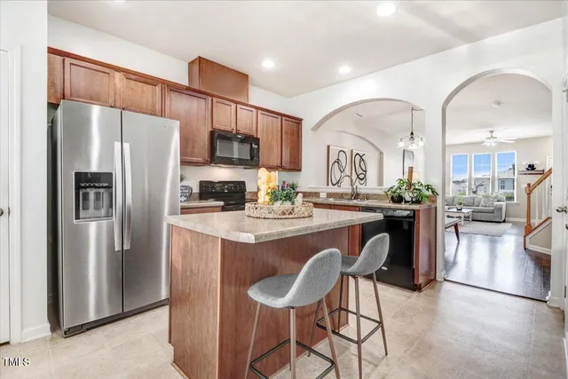 a kitchen with stainless steel appliances granite countertop a refrigerator a sink a stove and white cabinets