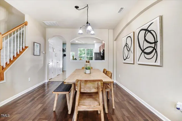 a view of a a dining room and livingroom with furniture wooden floor a chandelier