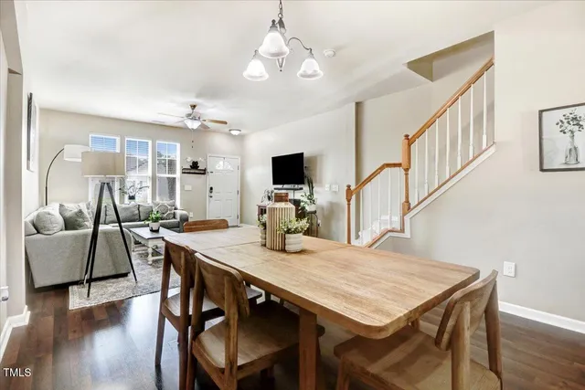 a kitchen with stainless steel appliances granite countertop a stove top oven a sink dishwasher a dining table and chairs with wooden floor