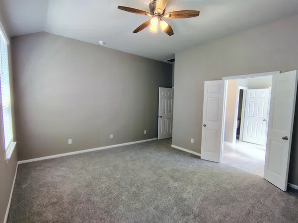 an empty room with closet and a chandelier fan