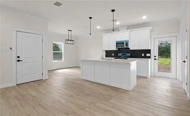 a kitchen with stainless steel appliances kitchen island granite countertop a stove a sink and a refrigerator with wooden floors