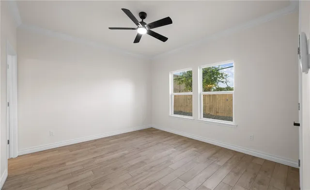 an empty room with wooden floor fan and windows