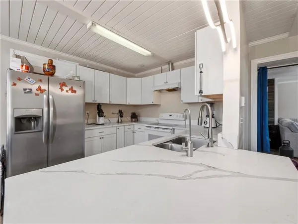 a kitchen with stainless steel appliances a refrigerator a sink a stove and white cabinets