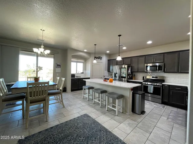 a kitchen with a sink a refrigerator and chairs