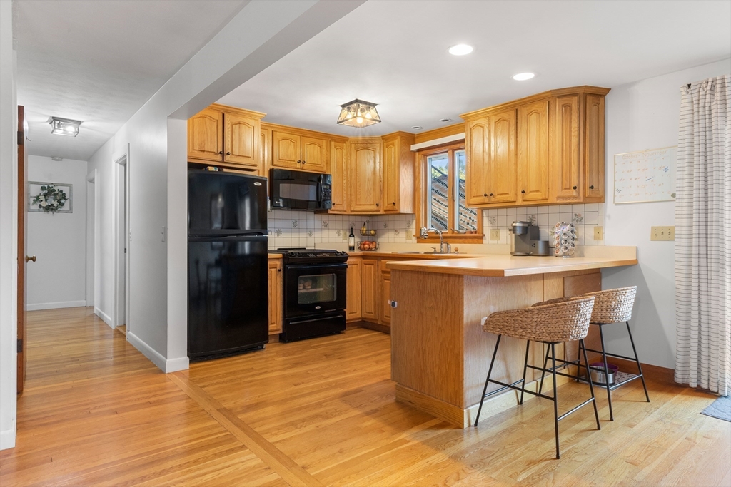 6 Auburn Road Salem, MA 01970 - Photo 10 of 32 a kitchen with stainless steel appliances granite countertop a refrigerator a sink dishwasher a stove and a dining table with wooden floor