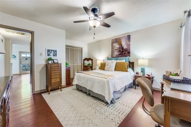 a bedroom with a bed and dresser with wooden floor