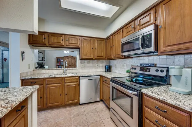 a kitchen with stainless steel appliances granite countertop a stove top oven a sink dishwasher and cabinets with wooden floor