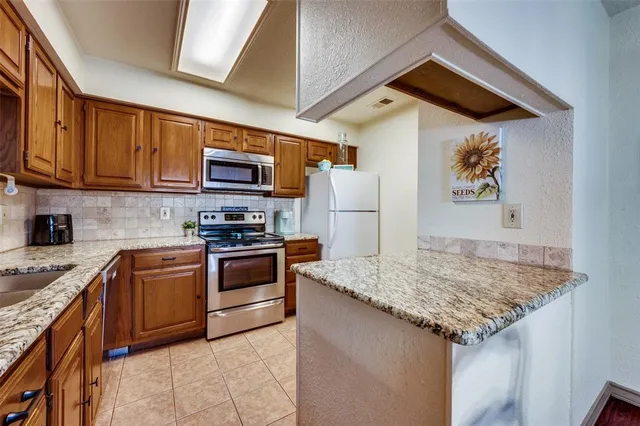 a kitchen with granite countertop wooden cabinets and a stove top oven