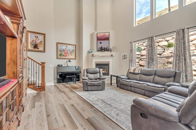 2543 East 700 South Springville, UT 84663 - Photo 23 of 73 Living room with light wood-type flooring, a glass covered fireplace, a high ceiling, and plenty of natural light