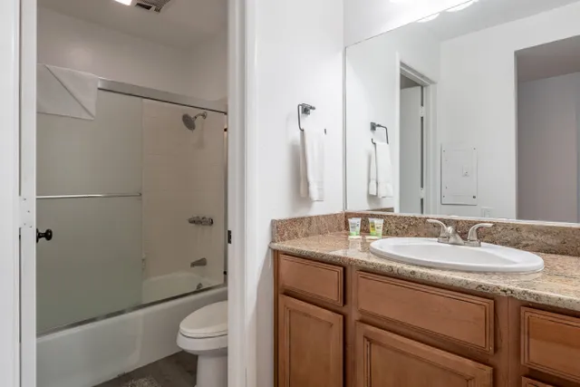 a bathroom with a granite countertop sink toilet and shower