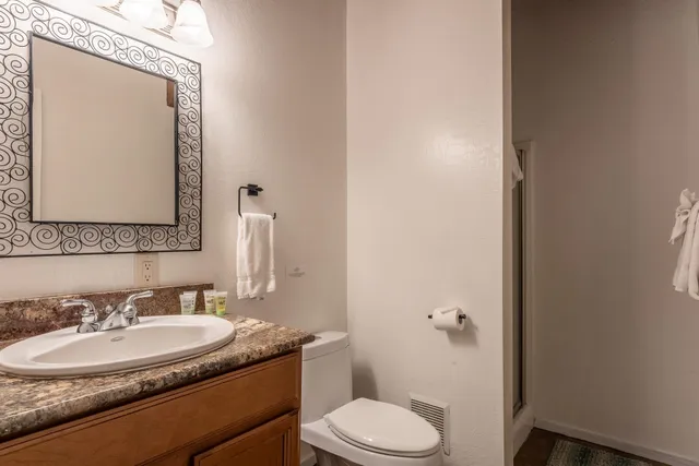 a bathroom with a granite countertop toilet sink and mirror