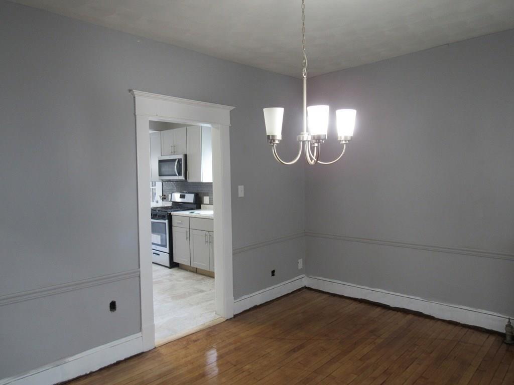 71 Meredith Street Springfield, MA 01108 - Photo 8 of 27 an empty room with wooden floor mirror and windows