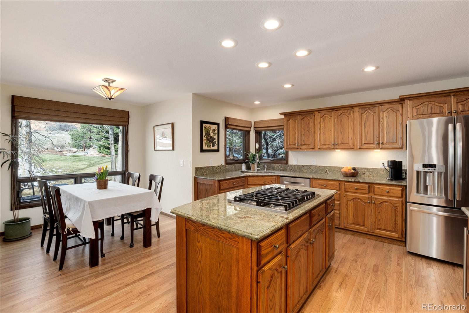 65 North Ranch Road Littleton, CO 80127 - Photo 9 of 44 a kitchen with stainless steel appliances granite countertop a stove refrigerator a dining table and chairs with wooden floor