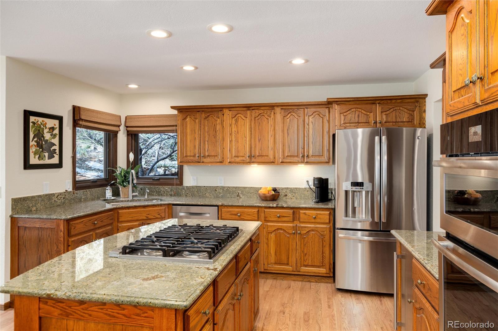 65 North Ranch Road Littleton, CO 80127 - Photo 10 of 44 a kitchen with stainless steel appliances granite countertop a refrigerator a sink dishwasher a stove and white countertops with wooden floor