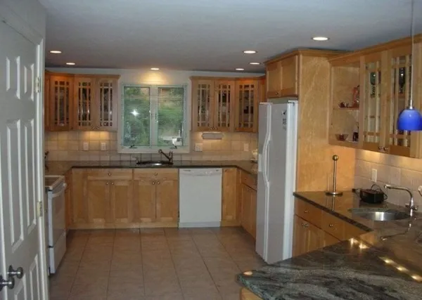a kitchen with kitchen island granite countertop a refrigerator and a sink