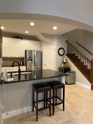 a kitchen with stainless steel appliances kitchen island granite countertop a sink a stove a refrigerator cabinets and chairs