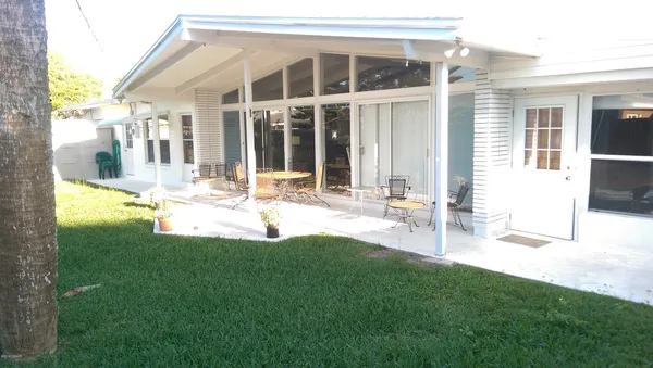 a view of backyard with table and chairs and wooden fence