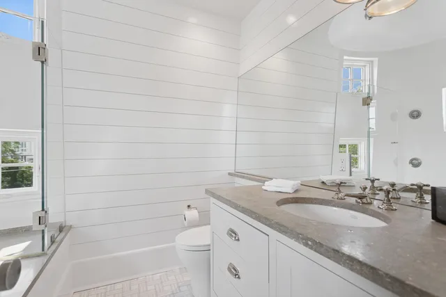 a bathroom with a granite countertop sink a toilet and shower
