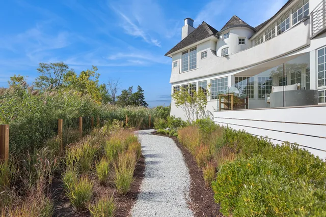 a view of a house with a small yard and large tree