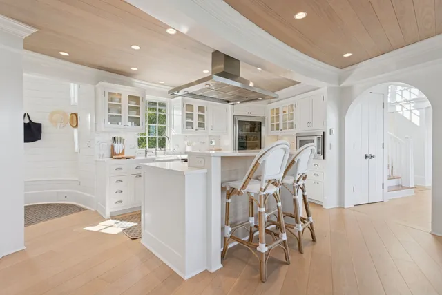 a kitchen with white cabinets and wooden floor