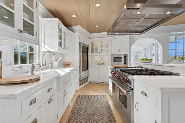 a large white kitchen with stainless steel appliances granite countertop a stove and a sink