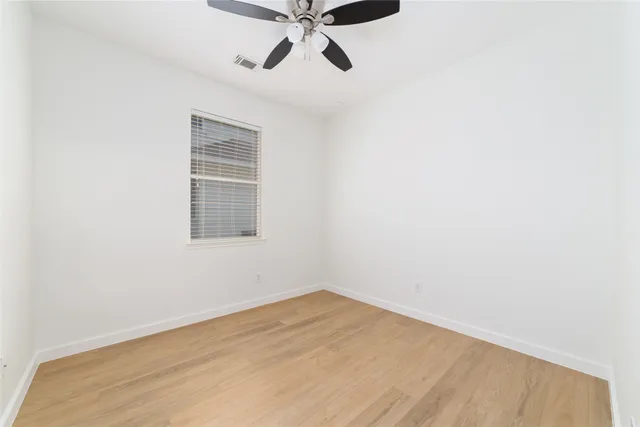 an empty room with a window and a ceiling fan