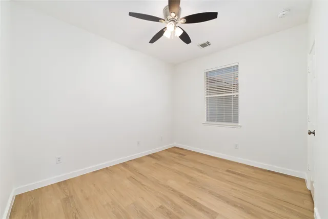 an empty room with a window and ceiling fan