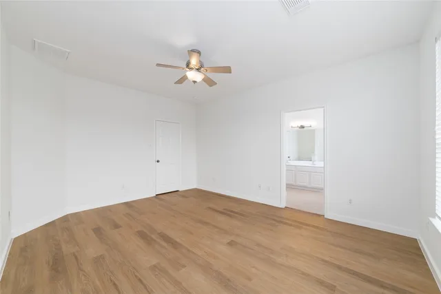 a view of empty room with wooden floor and ceiling fan