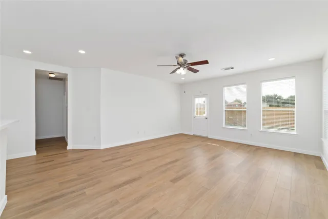 a view of an empty room with a window and wooden floor