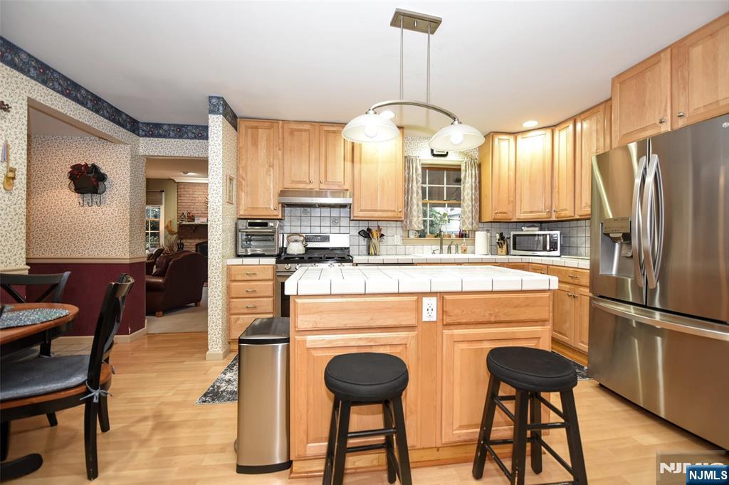 84 West Midland Avenue Paramus, NJ 07652 - Photo 11 of 37 a kitchen with stainless steel appliances a dining table chairs stove refrigerator and cabinets