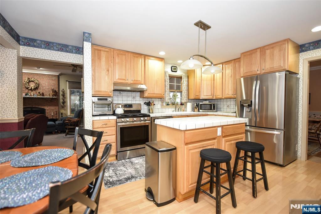 84 West Midland Avenue Paramus, NJ 07652 - Photo 10 of 37 a kitchen with stainless steel appliances kitchen island granite countertop a refrigerator a stove a sink a dining table and chairs with wooden floor