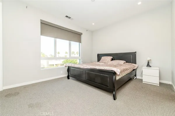 a bed sitting in a spacious bedroom next to a window