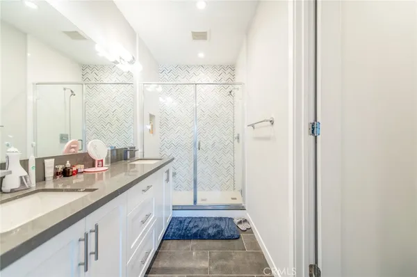 a bathroom with a double vanity sink and mirror with shower