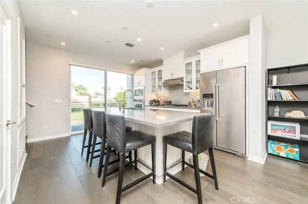 a kitchen with stainless steel appliances granite countertop a dining table chairs refrigerator and a window