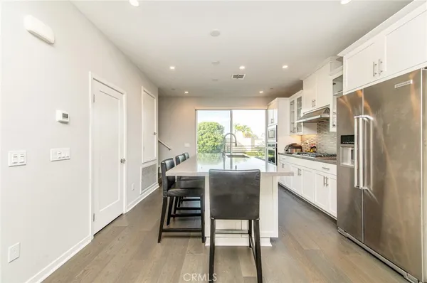 a kitchen with stainless steel appliances granite countertop a refrigerator a microwave oven a sink with island and chairs