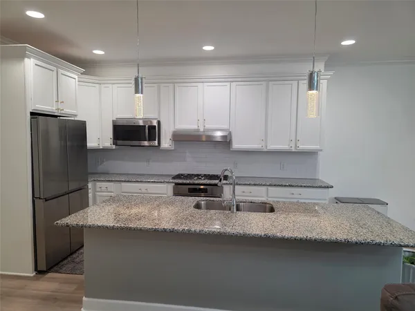 a kitchen with stainless steel appliances granite countertop a sink refrigerator and microwave