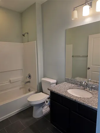 a bathroom with a granite countertop toilet a sink and a bathtub