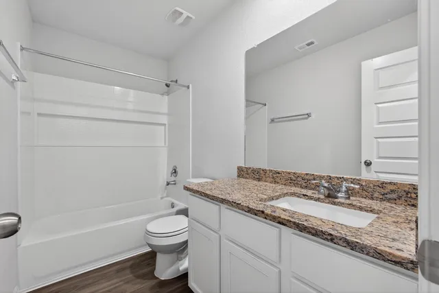 a bathroom with a granite countertop sink toilet a mirror and shower