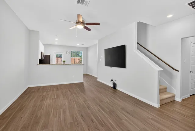 a view of a livingroom with wooden floor and a ceiling fan
