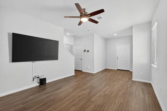 a living room with flat screen tv and a ceiling fan