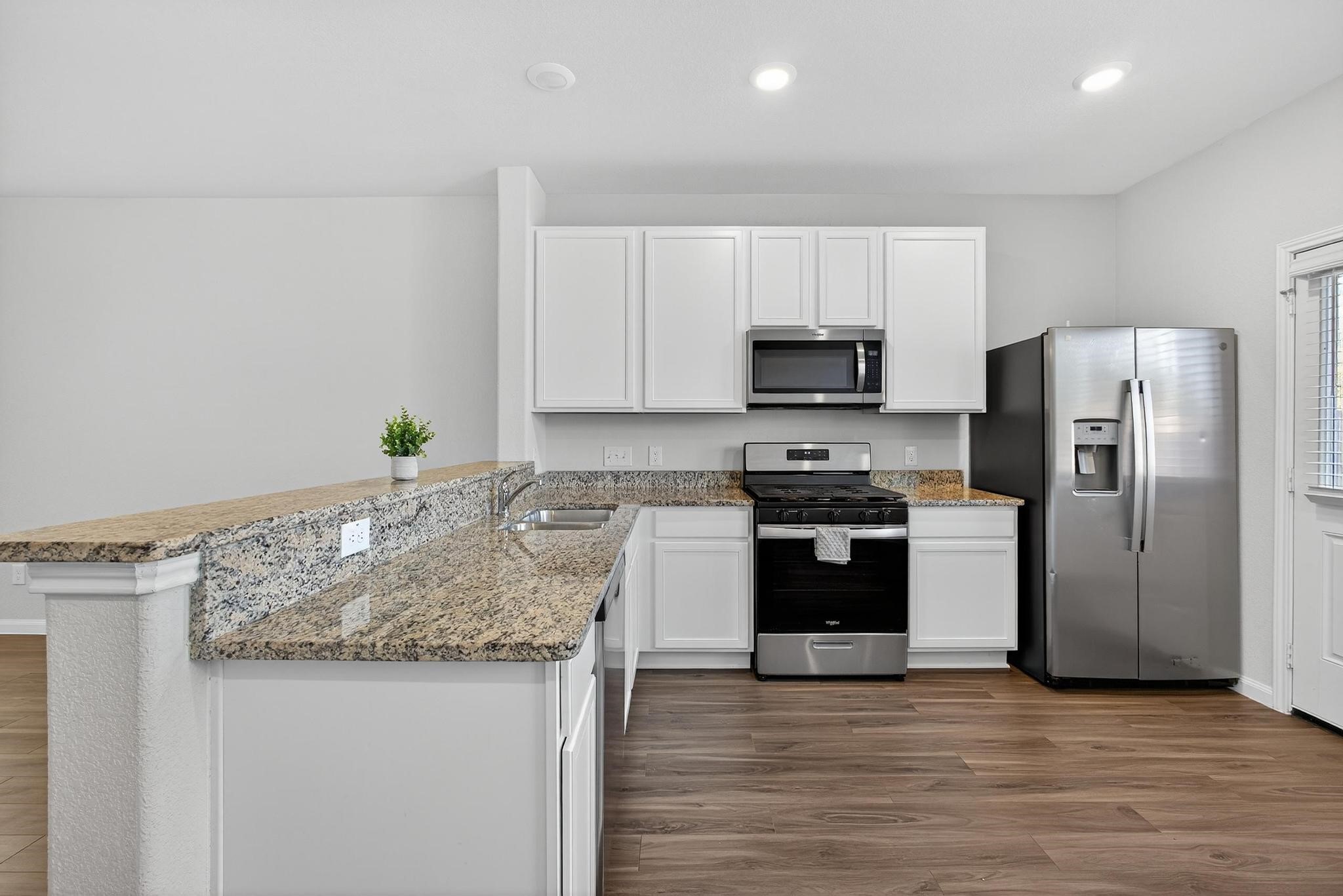 1409 Mount Bassie Trail Conroe, TX 77301 - Photo 4 of 26 a kitchen with granite countertop a refrigerator and a stove top oven
