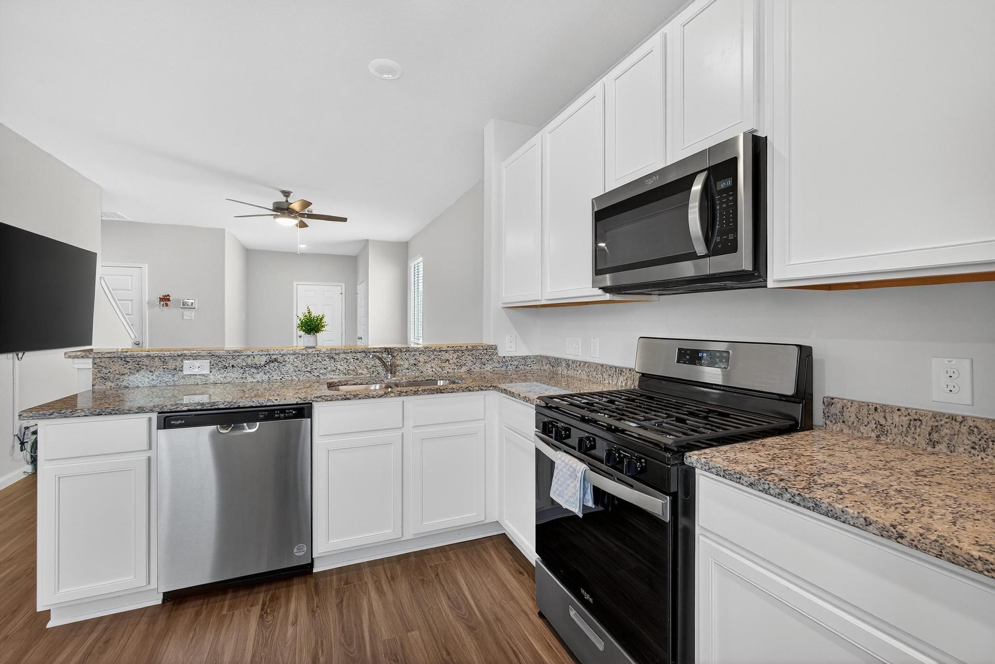 1409 Mount Bassie Trail Conroe, TX 77301 - Photo 6 of 26 a kitchen with stainless steel appliances granite countertop a stove and a microwave
