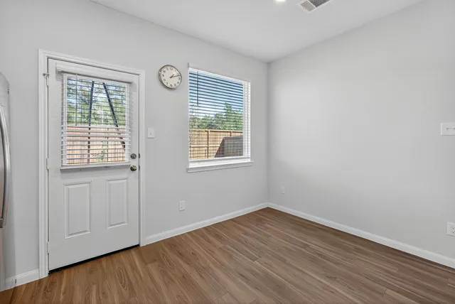 an empty room with wooden floor and windows
