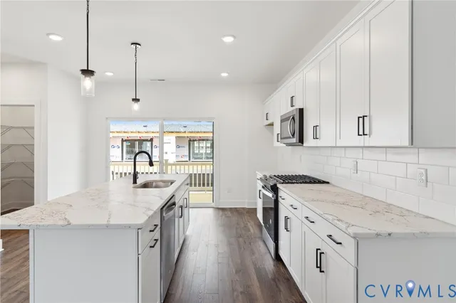 a kitchen with stainless steel appliances granite countertop a sink a stove and a wooden floors