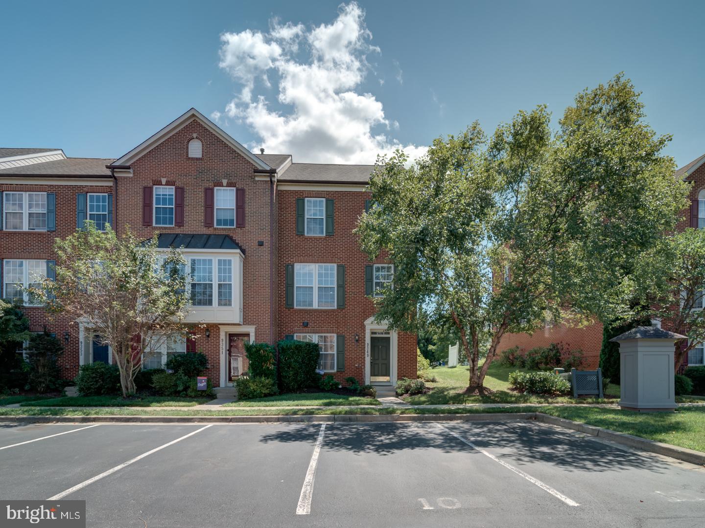 a view of a brick house next to a yard with large trees