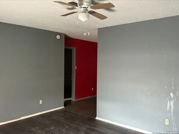 an empty room with wooden floor and fan