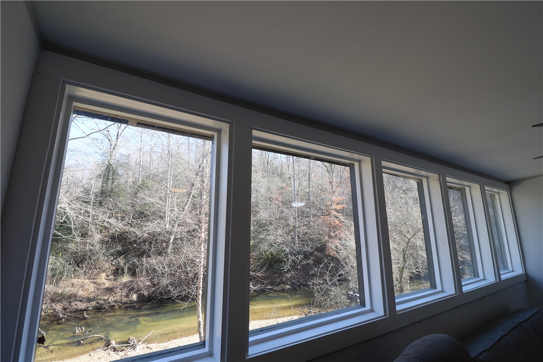 200 Laurel And Hardy Lake Road Marietta, SC 29661 - Photo 9 of 47 These expansive windows offer serene views of the surrounding natural landscape and flowing water.