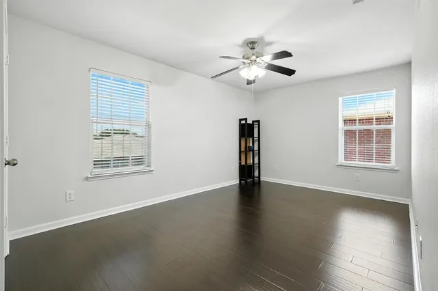 a view of an empty room with a window and wooden floor