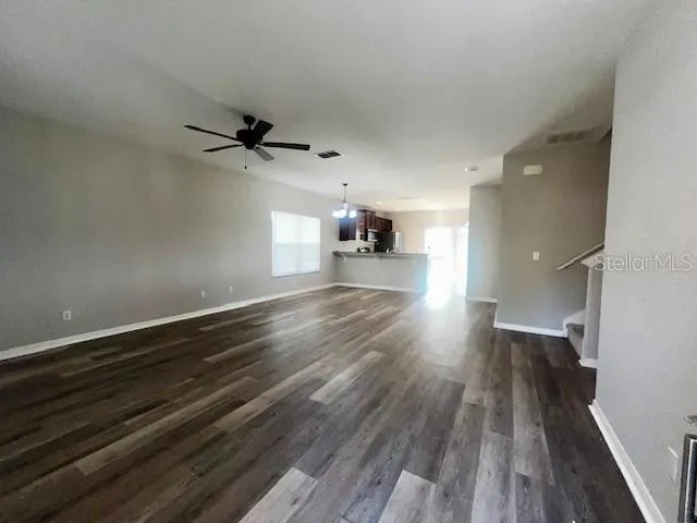 a view of a livingroom with a ceiling fan wooden floor and a ceiling fan