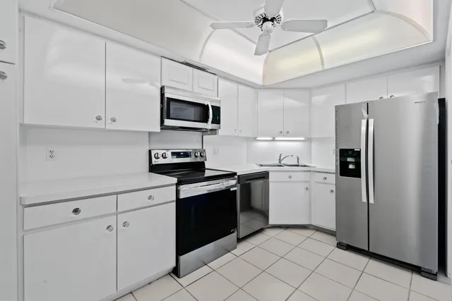 a kitchen with stainless steel appliances granite countertop a refrigerator a sink dishwasher a stove and white cabinets